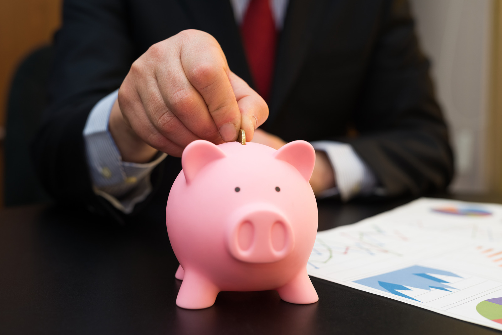 Businessman putting money in a piggy bank